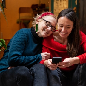 Two people laughing and looking at a phone screen